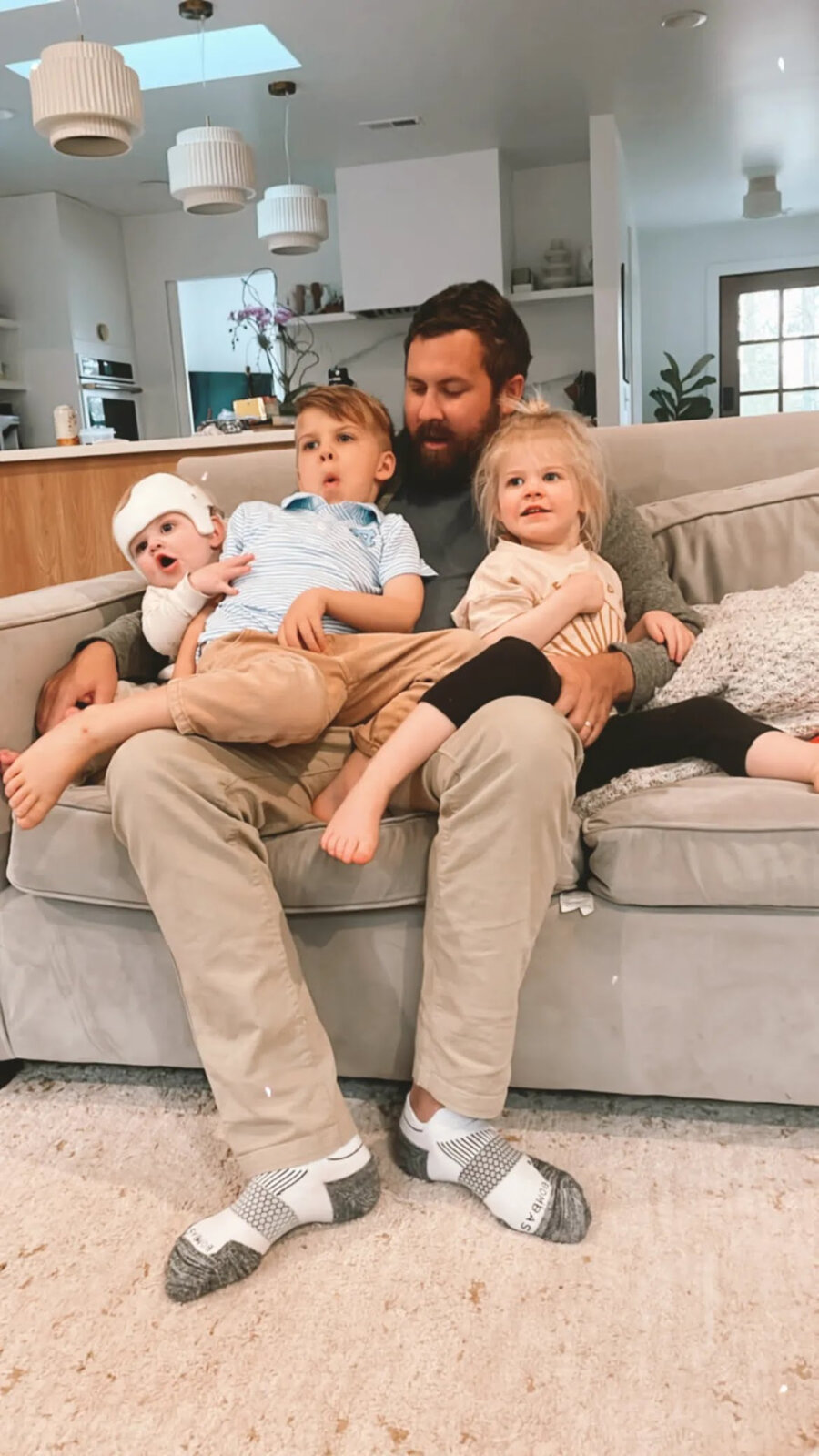 Bryan on the couch with his three kids piled on his lap