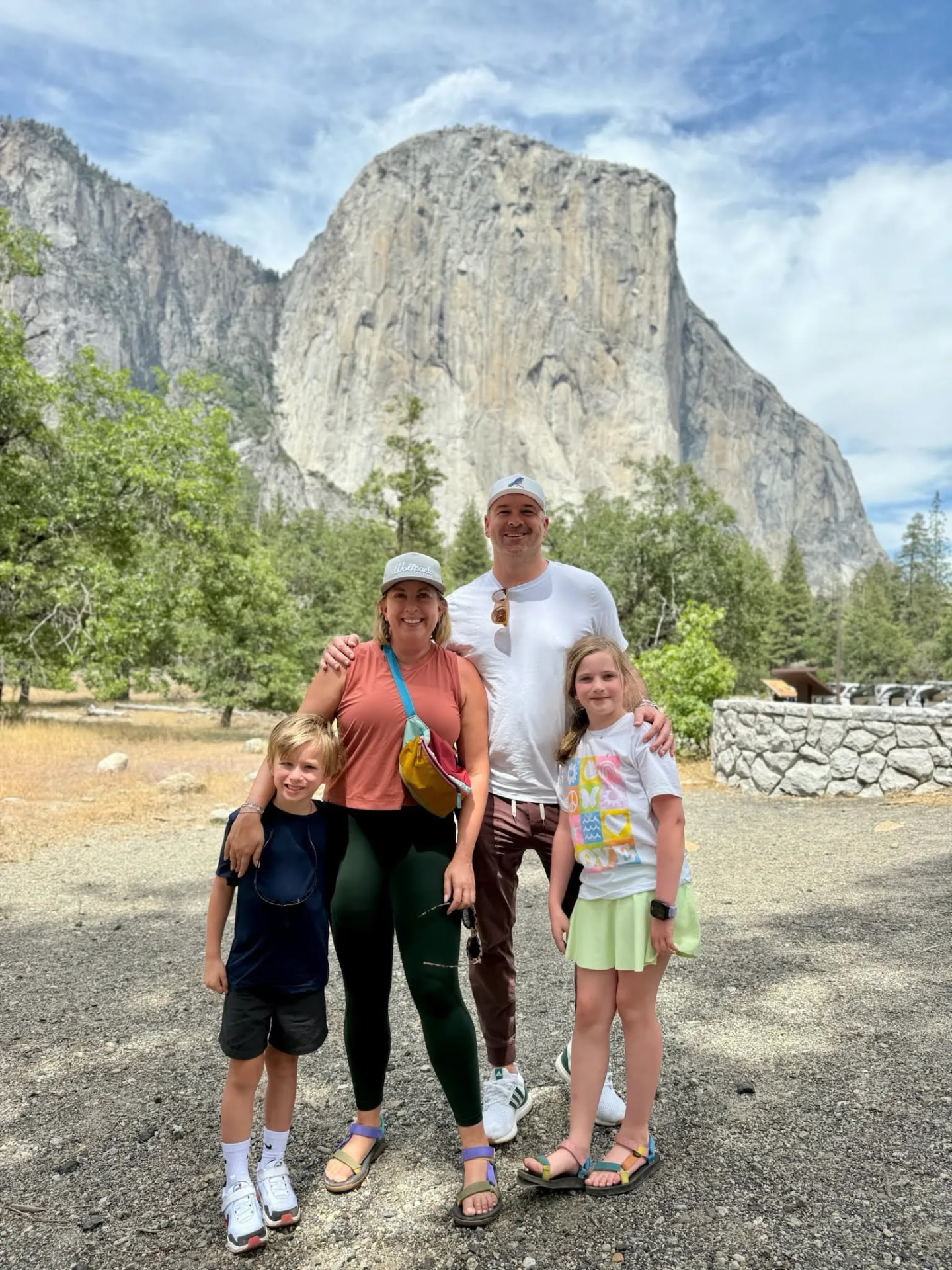 Ward and Emily standing with their children, Norah and Henry, in front of a granite cliff