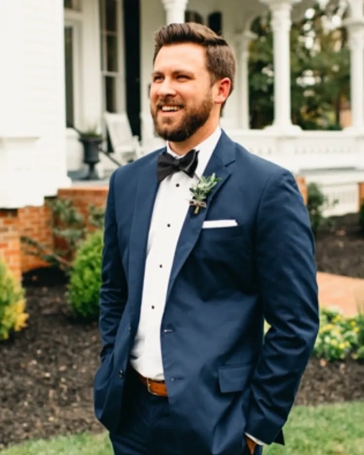 Bryan smiling in a navy suit and bow tie