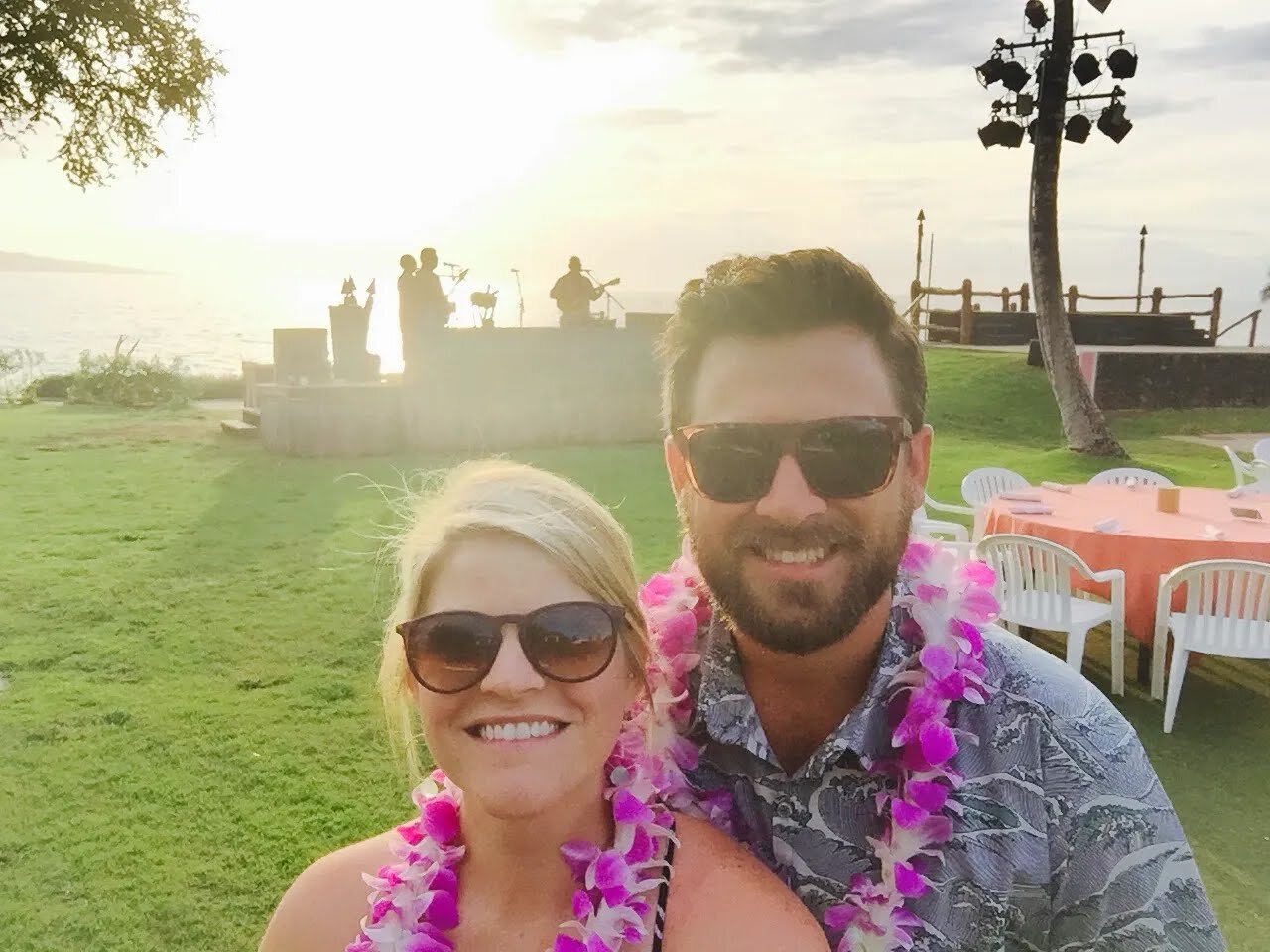 Bryan and Mandy wearing leis by the ocean at sunset in Hawaii